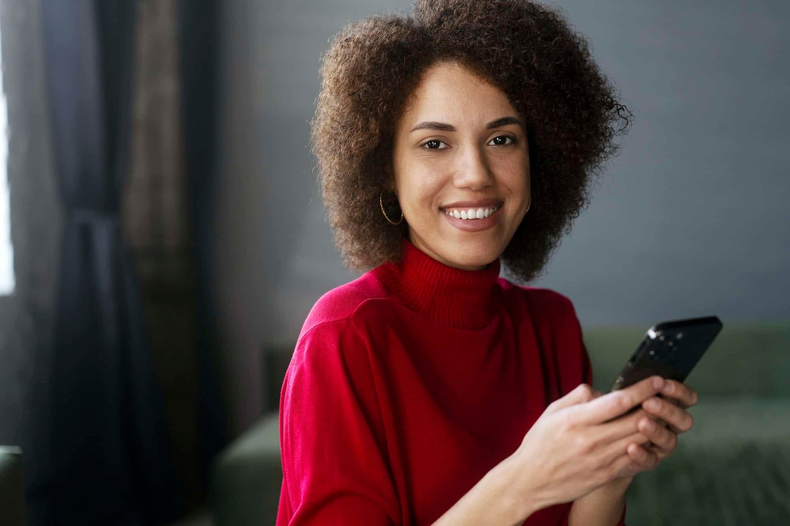 african american woman in red casual attire using mobile phone working online text messaging